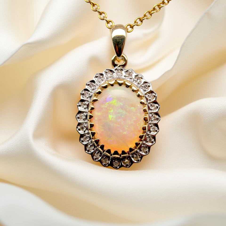 Opal pendant with gold frame and chain on white fabric