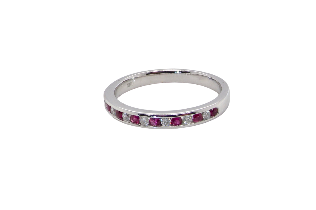 A white gold half hoop eternity ring. Set with seven round rubies and six brilliant cut white diamonds