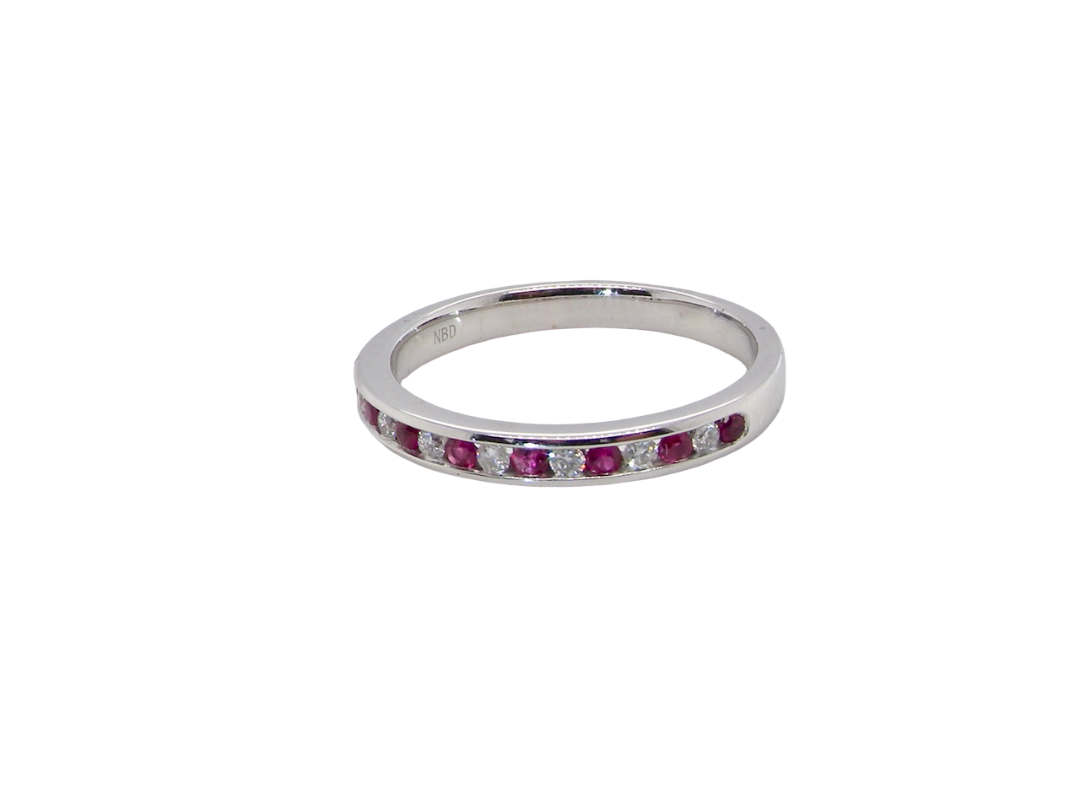 A white gold half hoop eternity ring. Set with seven round rubies and six brilliant cut white diamonds