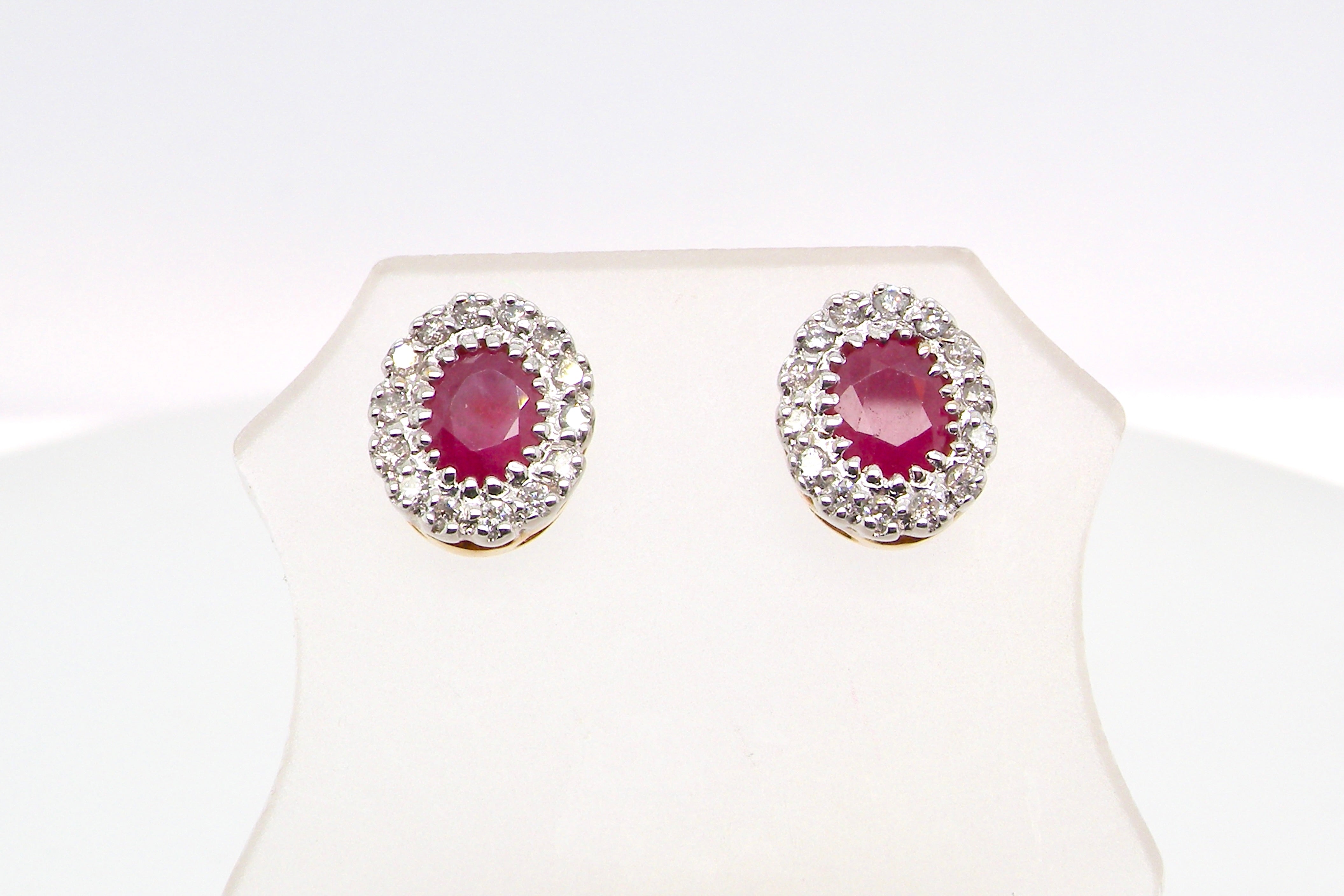 Pair of earrings with red gemstones and diamond-like accents on a white background
