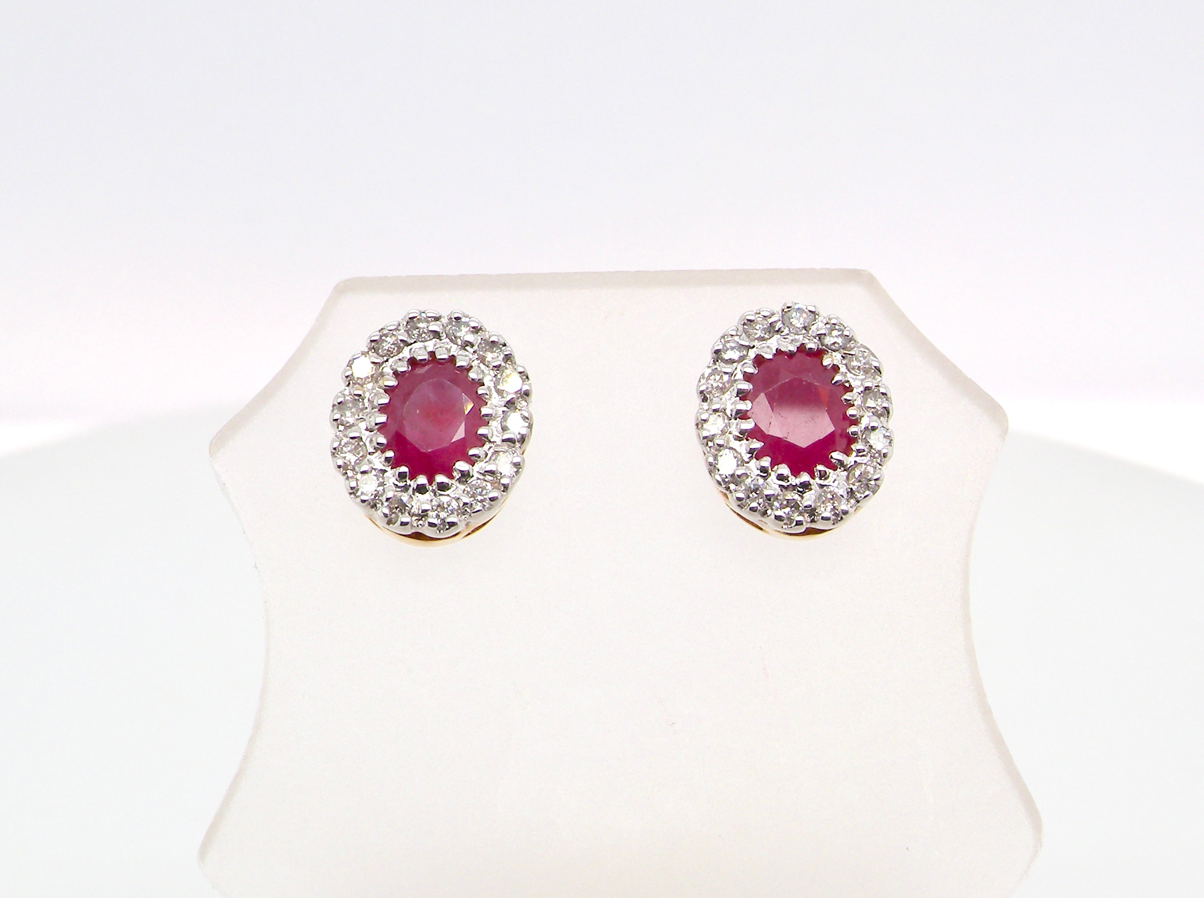 Pair of earrings with red gemstones and diamond-like accents on a white background