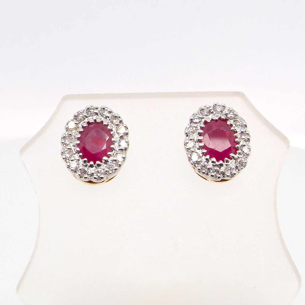 Pair of earrings with red gemstones and diamond-like accents on a white background