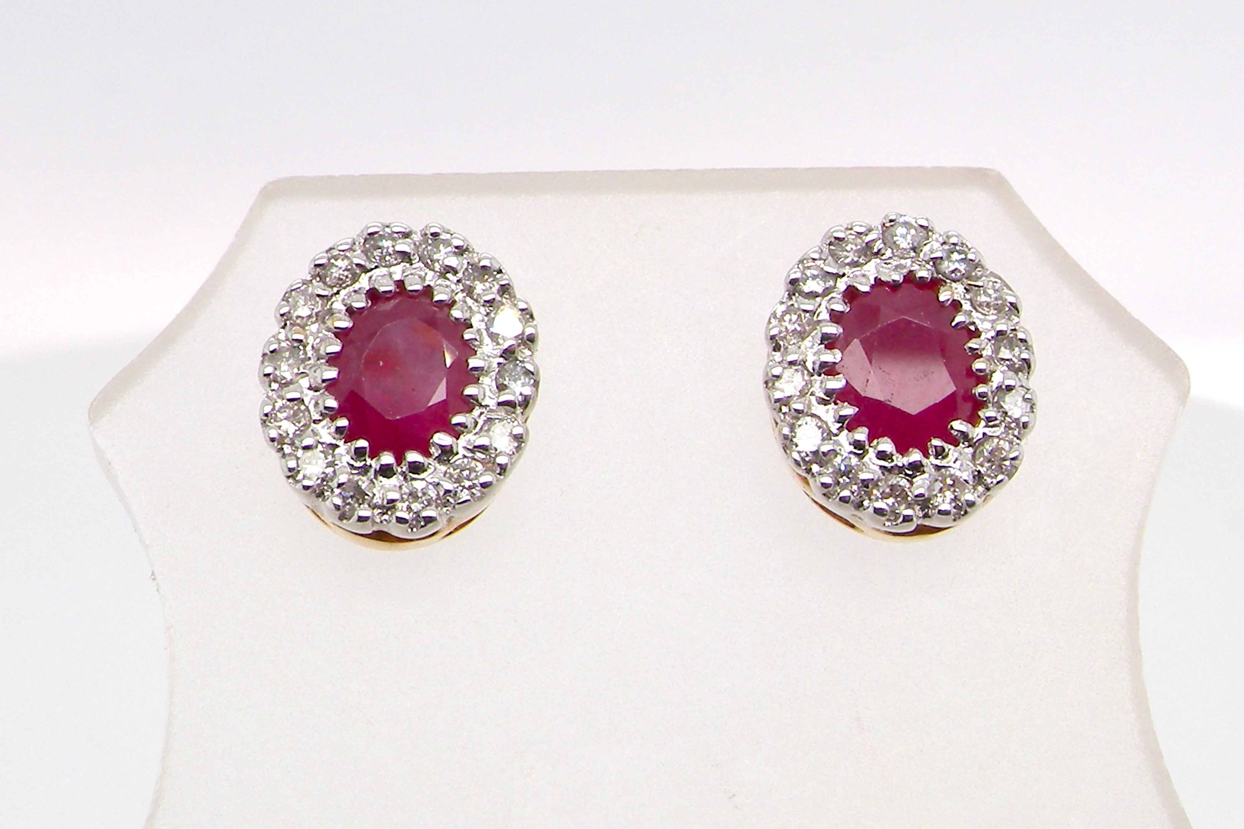 Pair of earrings with red gemstones and diamond-like accents on a white background