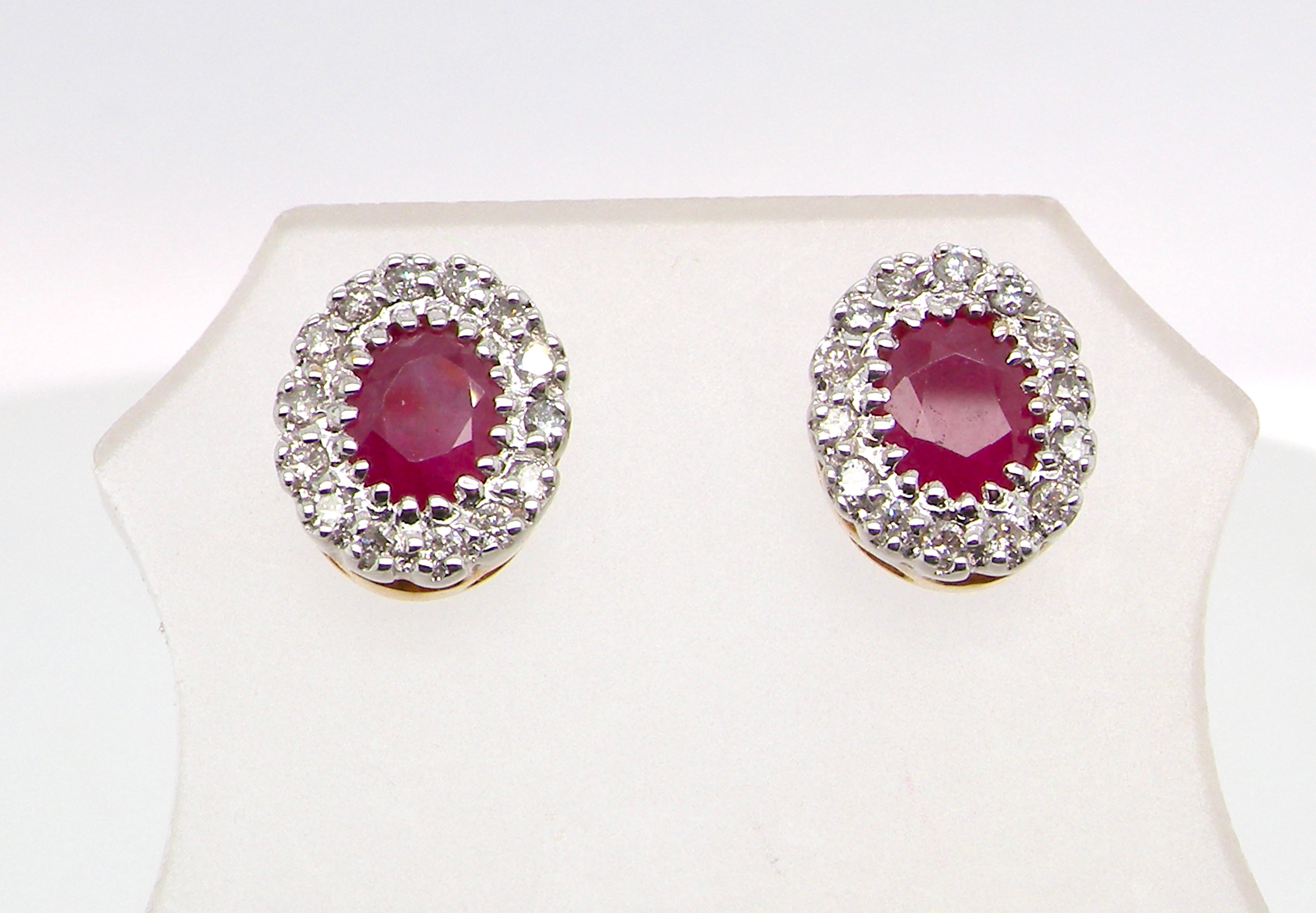 Pair of earrings with red gemstones and diamond-like accents on a white background