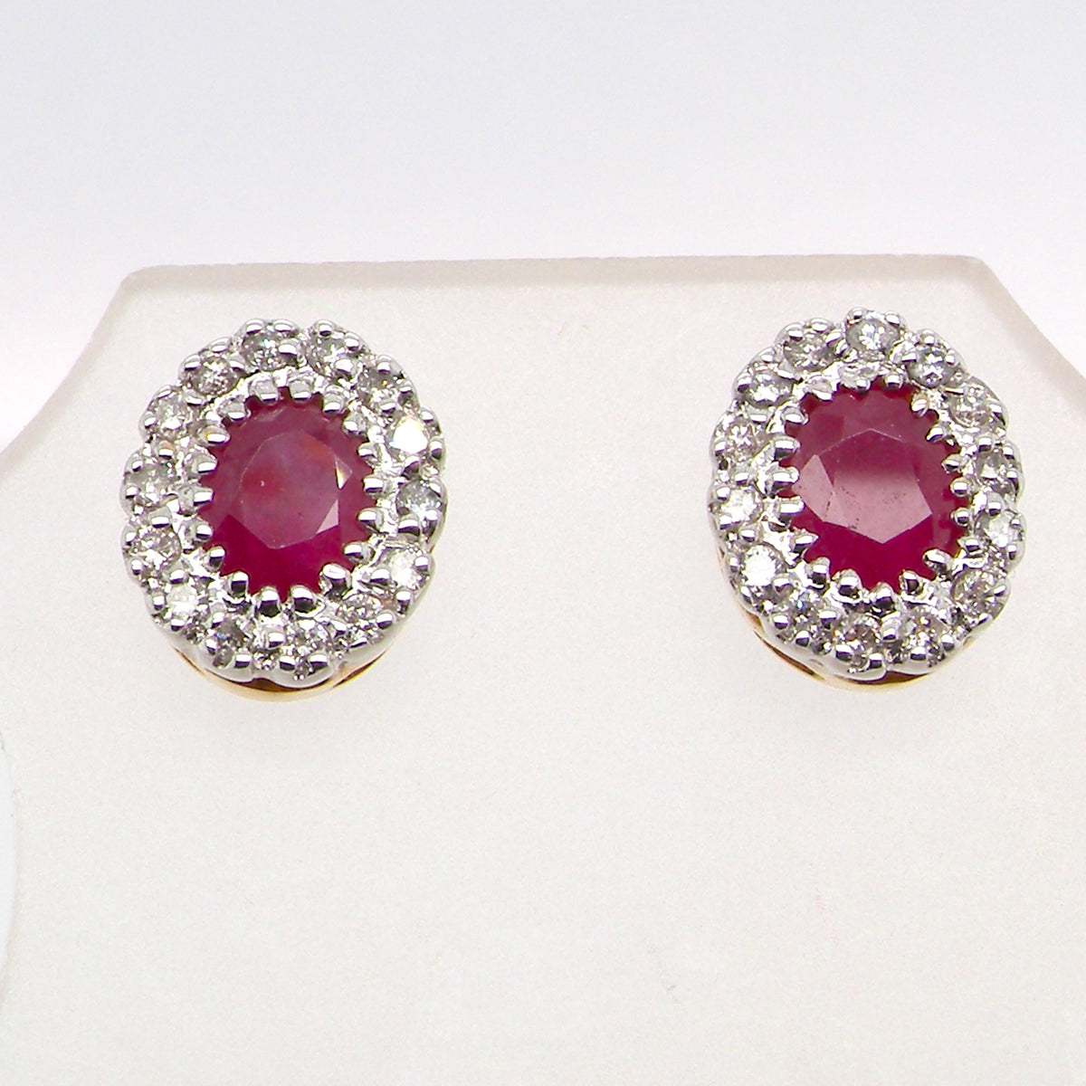 Pair of earrings with red gemstones and diamond-like accents on a white background