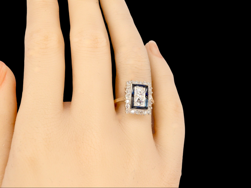 A fine Art Deco sapphire and diamond cluster ring on a finger