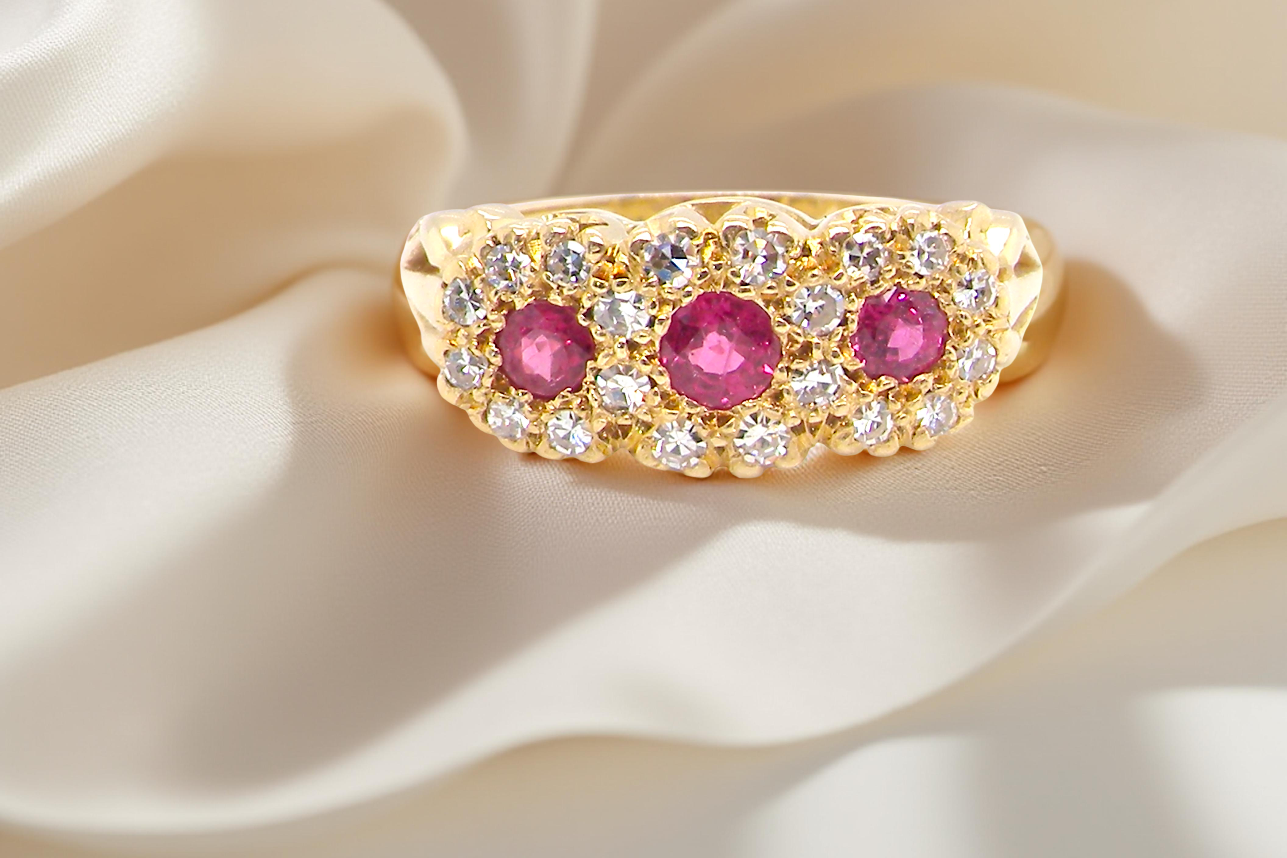 Gold ring with pink gemstones on a beige fabric background