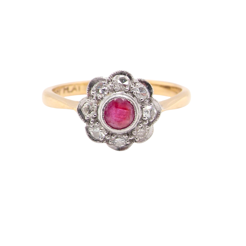 Gold ring with a red gemstone and diamond accents on a white background