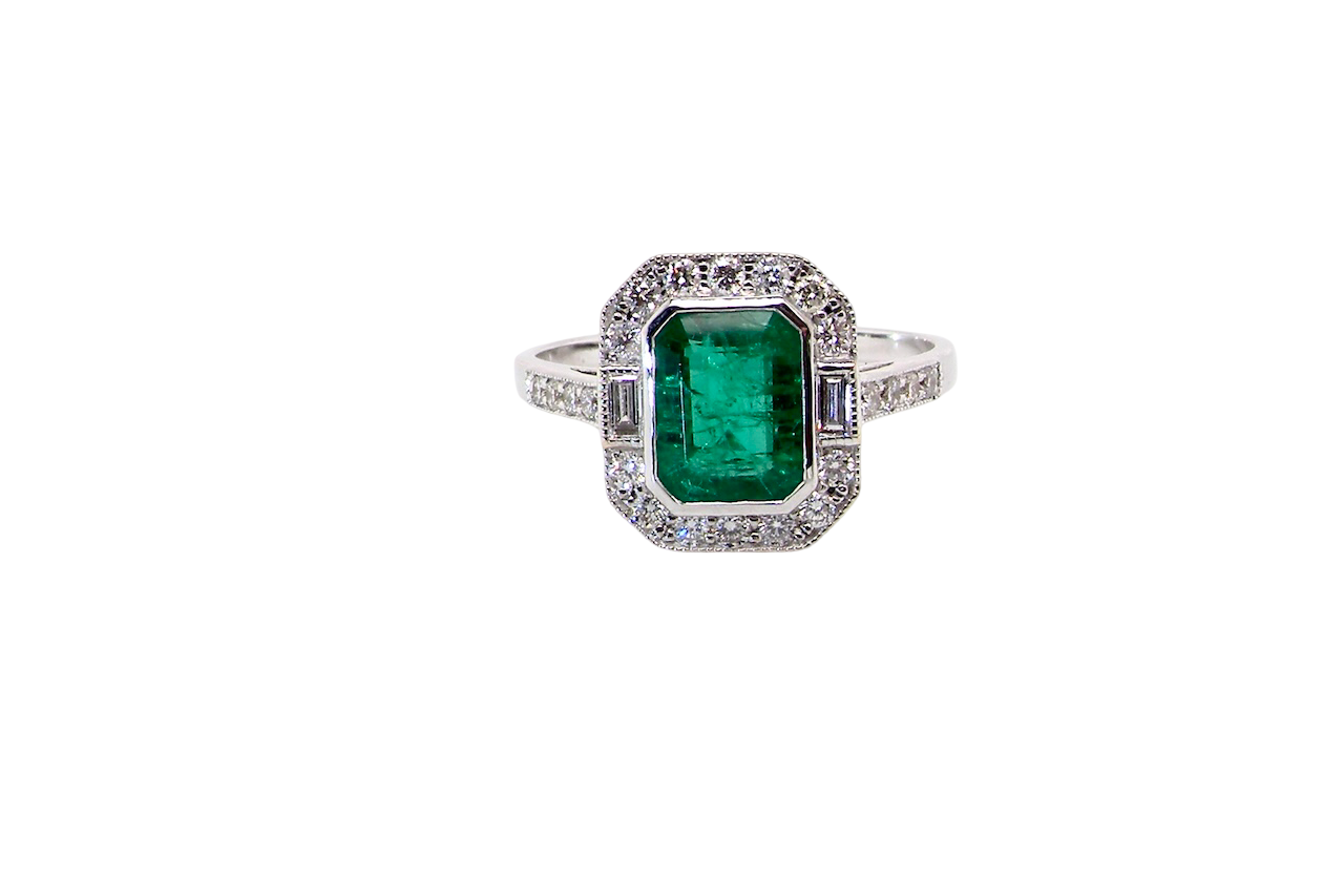 Ring with a green emerald and diamond accents on a white background