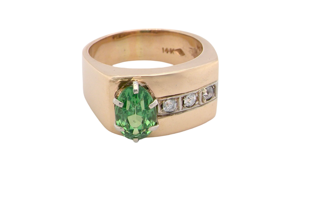 An image of a 14 carat gold dress ring set with an oval green tsavorite garnet and three small brilliant cut white diamonds