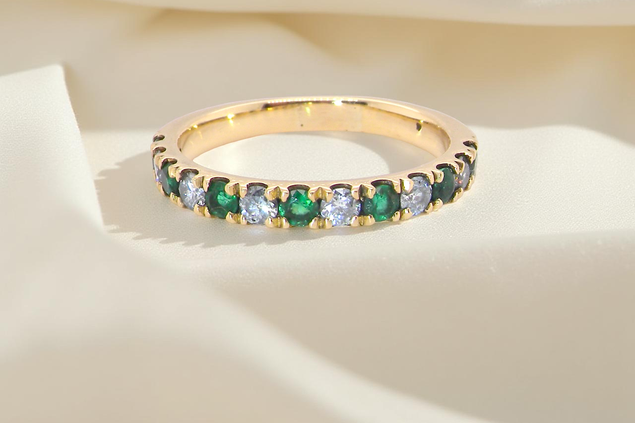 gold eternity ring with green and clear gemstones