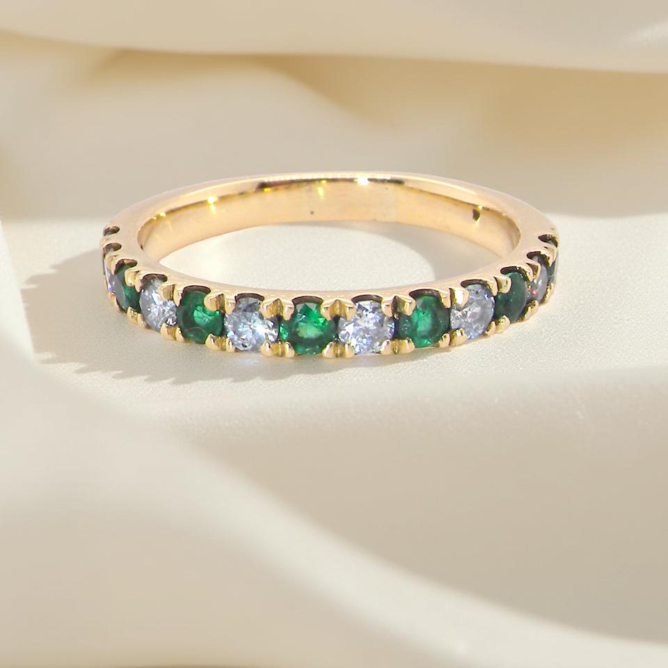 gold eternity ring with green and clear gemstones