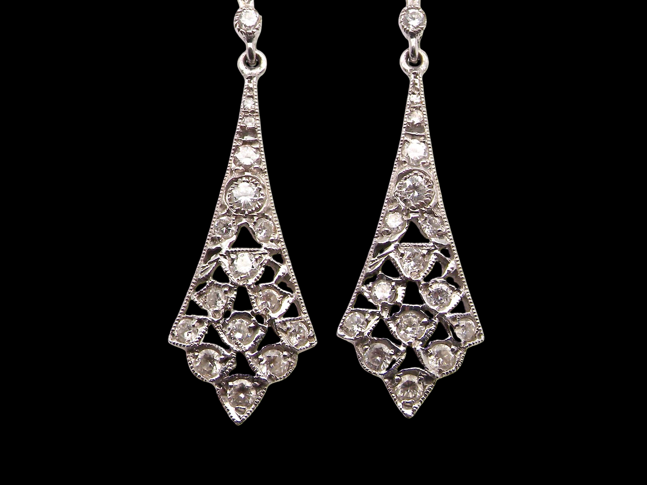 Designed in the elegant style of the 1920s, these sophisticated drop earrings are crafted in white gold.