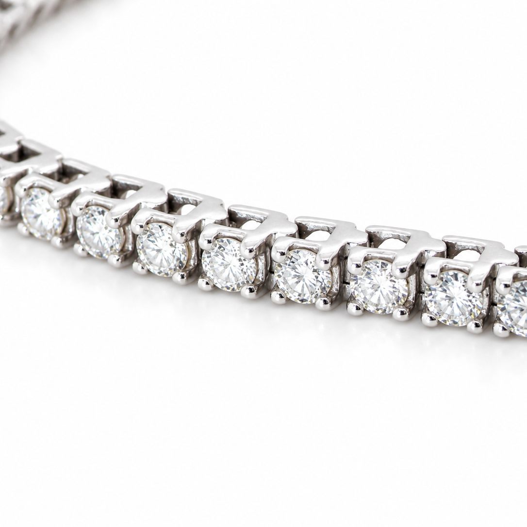 A close-up of a diamond tennis bracelet set in a silver-colored metal, shown on a clean white background.