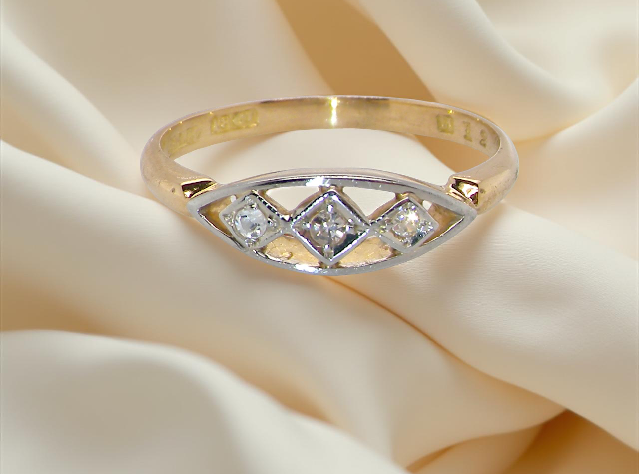 Gold ring with diamonds on a soft beige fabric background