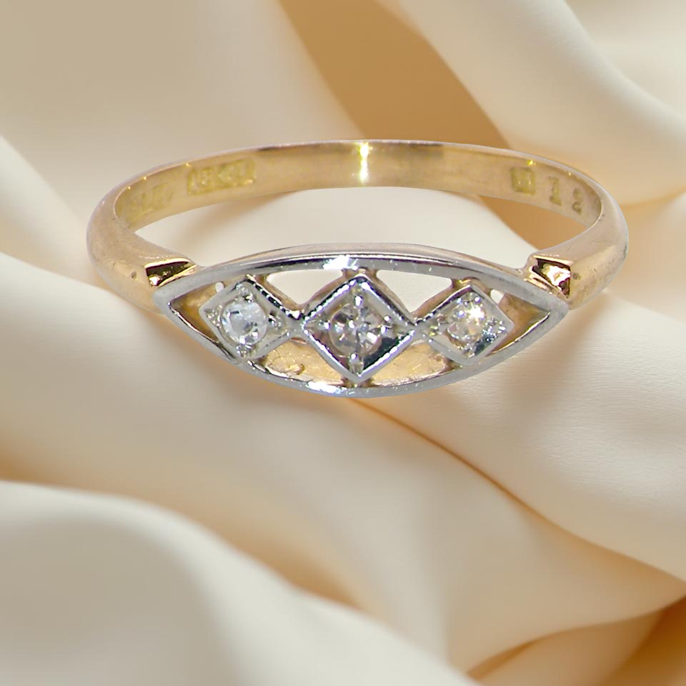 Gold ring with diamonds on a soft beige fabric background