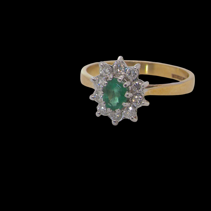 Features to the centre an oval shaped emerald, 5.5x4.5mm (est 0.35 carats) deep green colour. 