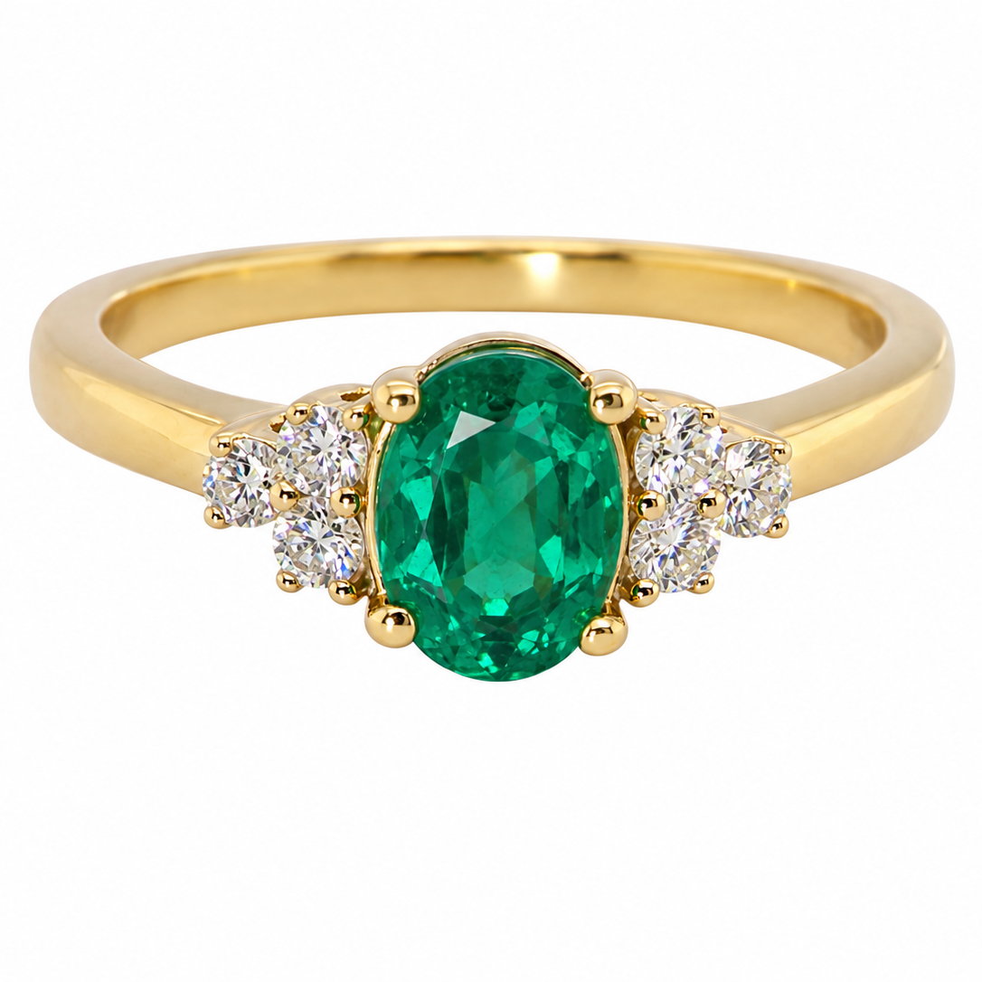 A yellow gold ring featuring an oval-cut green emerald center stone, flanked by small round clear stones on each side, set against a plain white background.