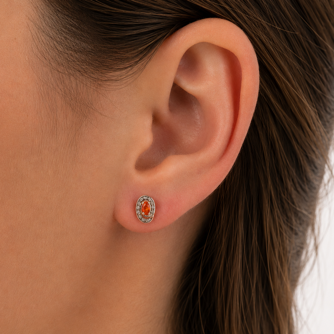 Pair of earrings with fire opals on a ear
