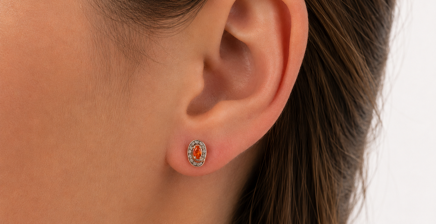 Pair of earrings with fire opals on a ear