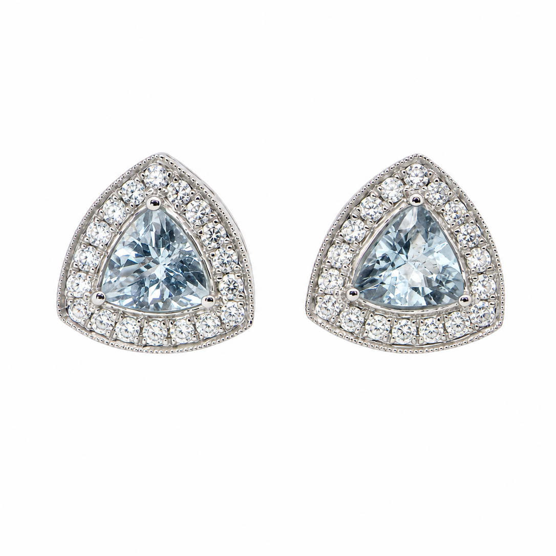 A fine pair of 18 carat white gold cluster earrings, each containing a trapeze cut aquamarine 6x6x6mm (1 carat) surrounded by eighteen x 0.02 carat brilliant cut white diamonds.
