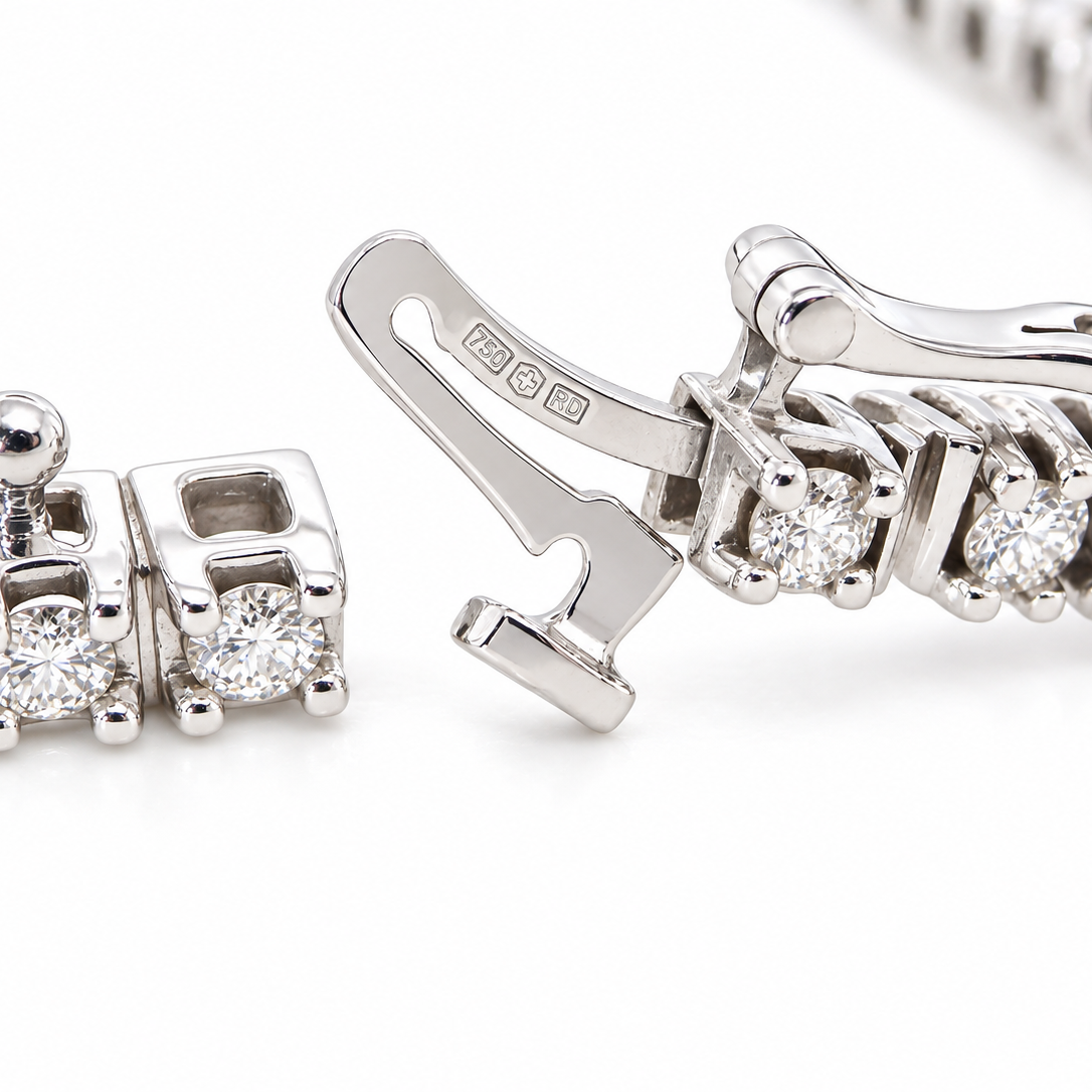 Close-up of a silver-toned tennis bracelet showing the clasp mechanism and a section of the linked chain with clear gemstones on a white background.