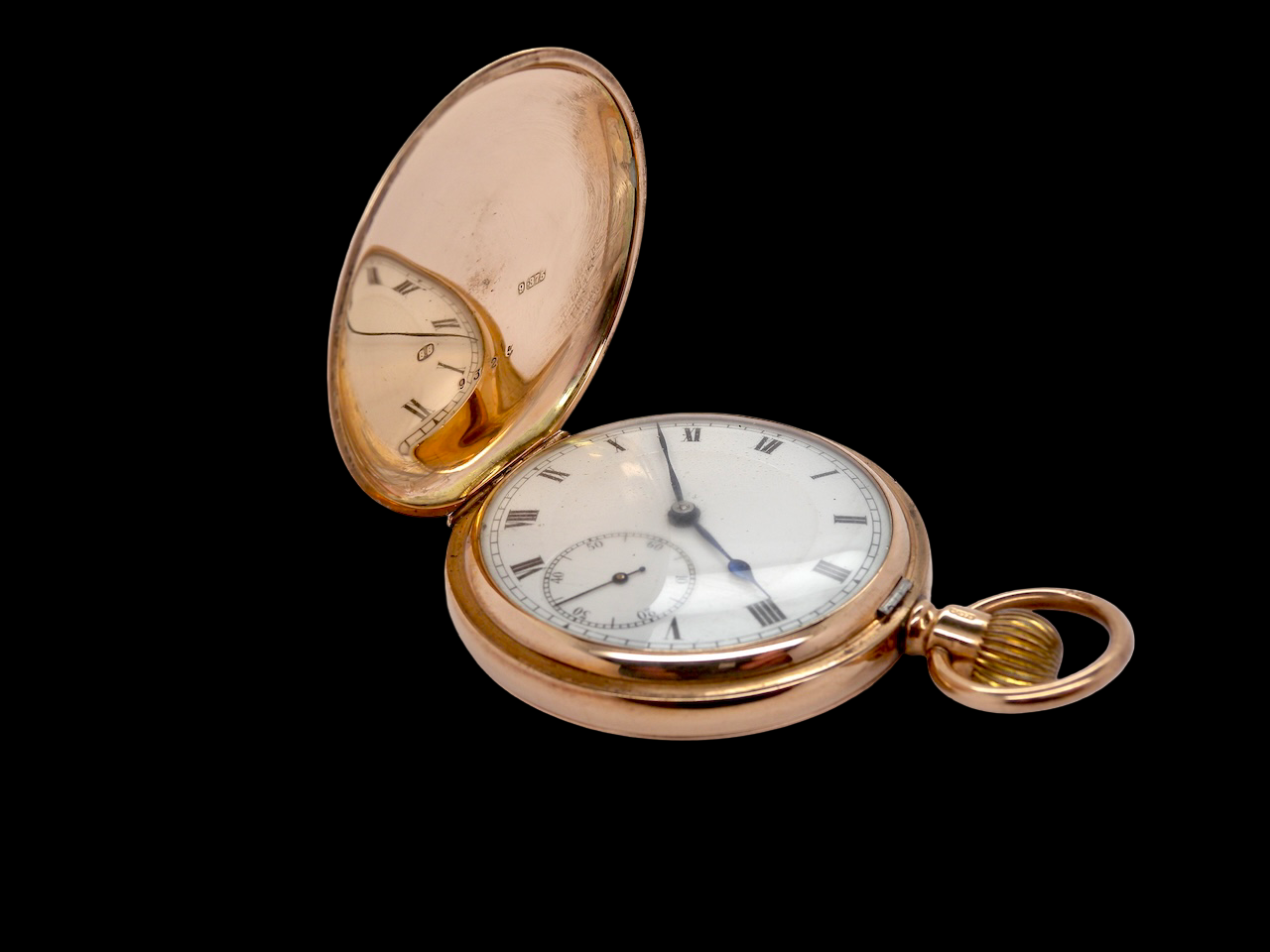 Rose gold pocket watch with open face on a black background