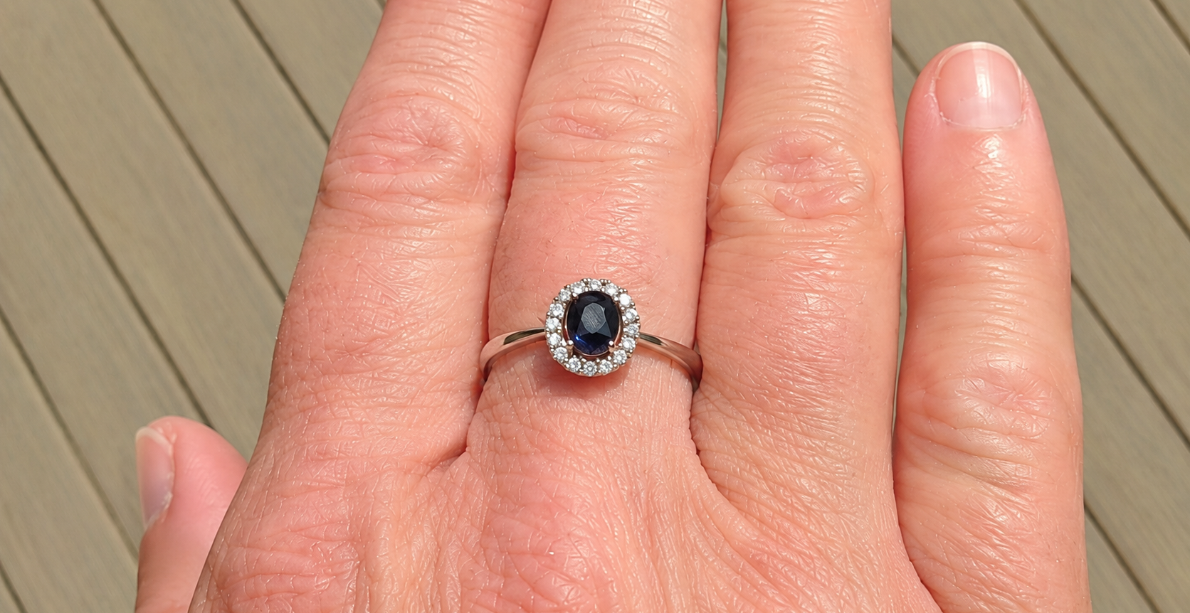 A sapphire & diamond cluster ring on a hand