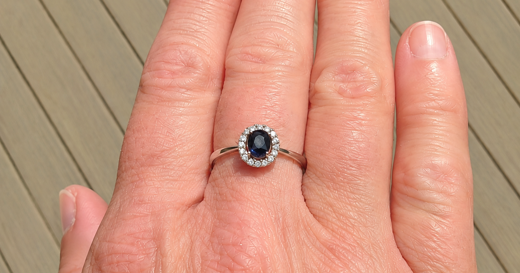 A sapphire & diamond cluster ring on a hand