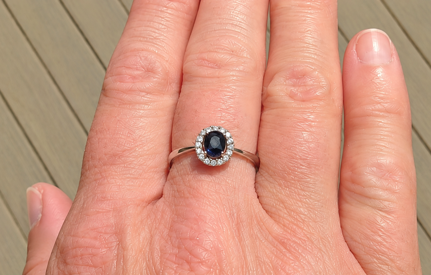 A sapphire & diamond cluster ring on a hand