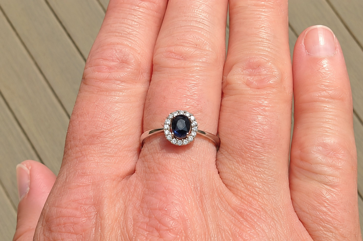A sapphire & diamond cluster ring on a hand