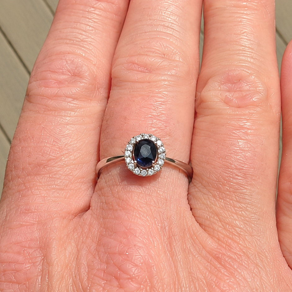 A sapphire & diamond cluster ring on a hand
