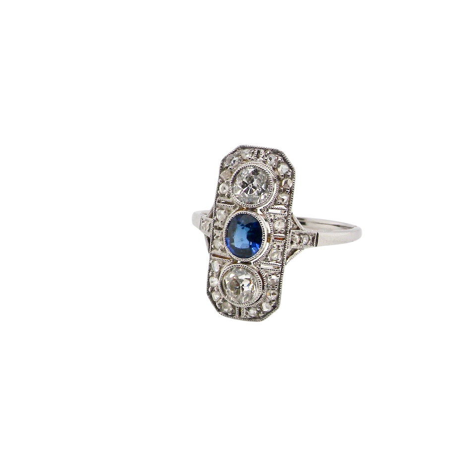 The plaque design has at its centre a mid to dark blue sapphire, 5x4mm (est 0.40 carats) mille grain set. Above and below to Old European Cut white diamonds. Each one estimated at 0.40 carats (4.8mm) Colour H-j, clarity Si.