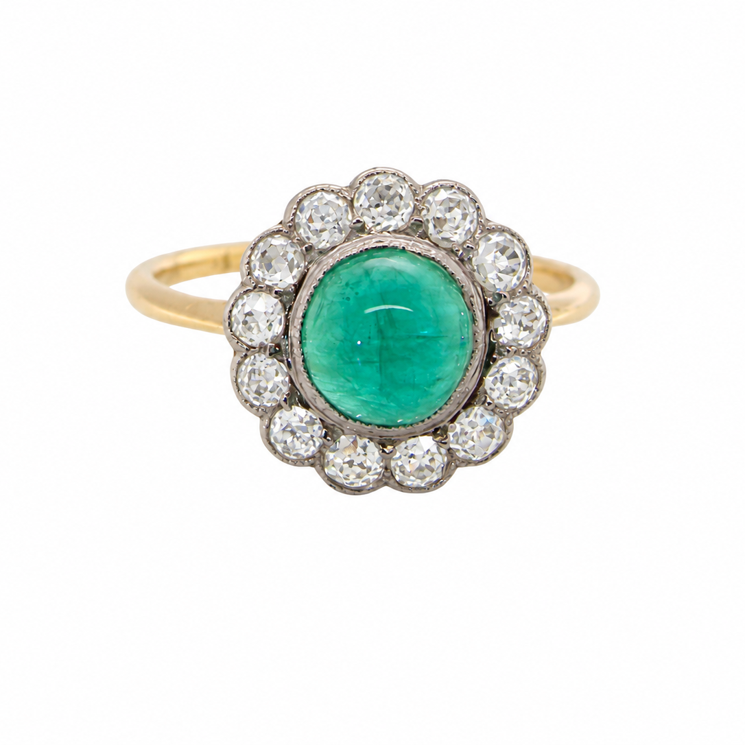 An antique cluster ring. The centre stone a cabouchon cut emerald