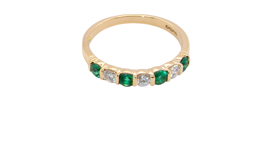 above An 18 carat yellow gold half hoop eternity ring. Set with four bright green emeralds, each 3mm diameter (est each 0.10 carats) .