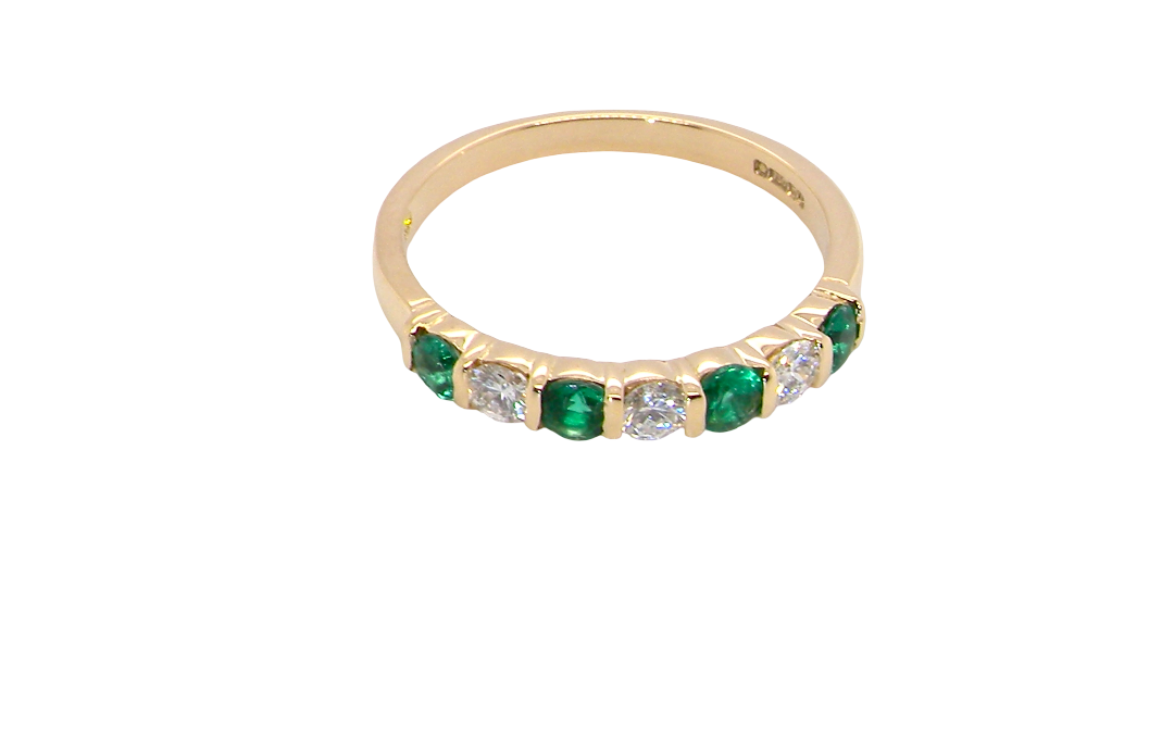 above An 18 carat yellow gold half hoop eternity ring. Set with four bright green emeralds, each 3mm diameter (est each 0.10 carats) .