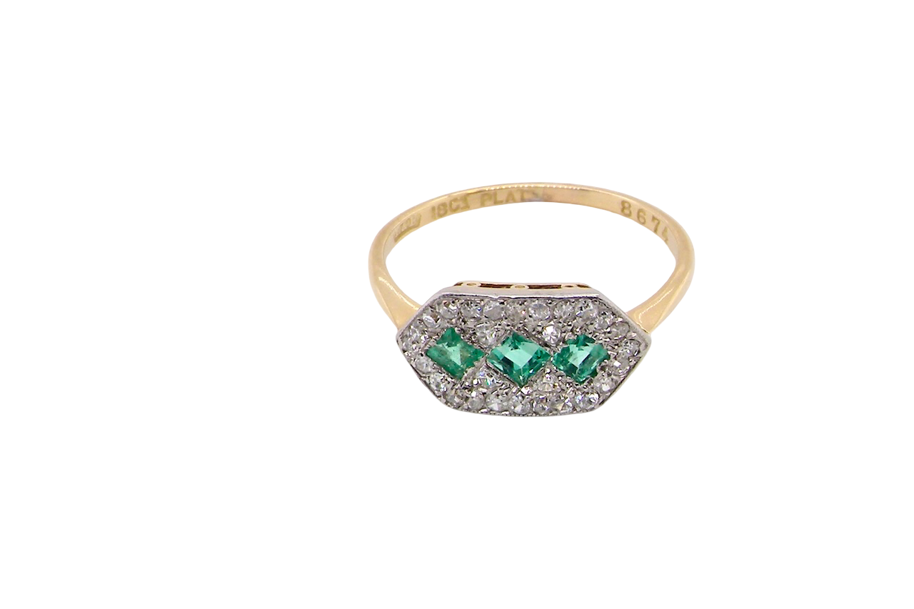 above fine Edwardian era cluster ring, beautifully handcrafted with a trio of vibrant emeralds surrounded by a halo of antique old-cut diamonds.