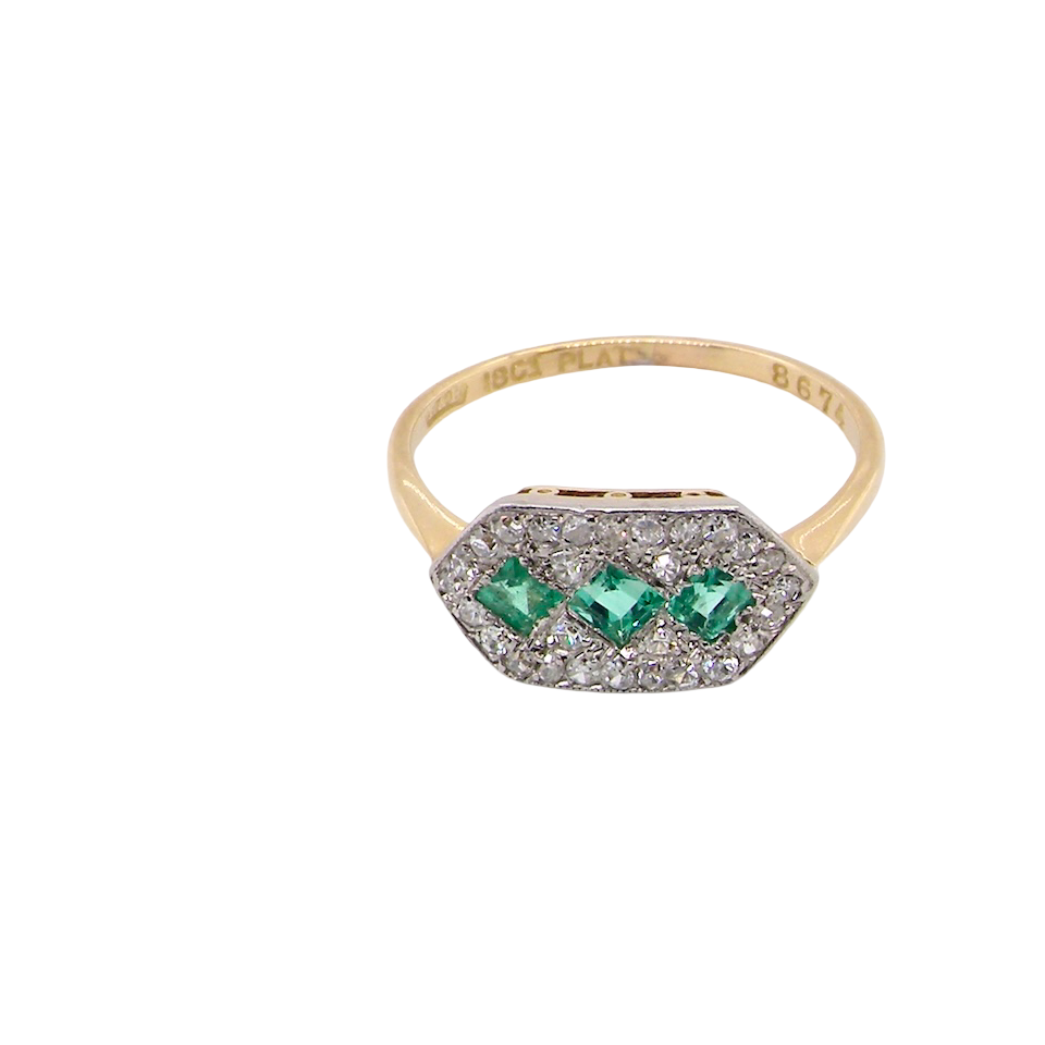 above fine Edwardian era cluster ring, beautifully handcrafted with a trio of vibrant emeralds surrounded by a halo of antique old-cut diamonds.