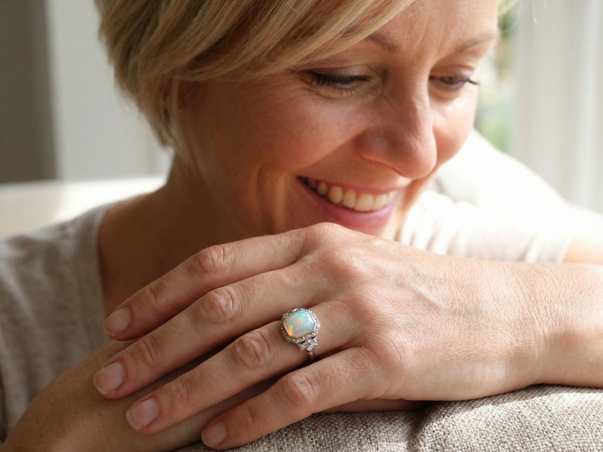 adoring a cabouchon cut opal shown is cushion shaped, measures 15x13 (5.78 carats) displaying a mass of vibrant colours, from flashes of fireglow orange, luminous greens, and lavender purples.