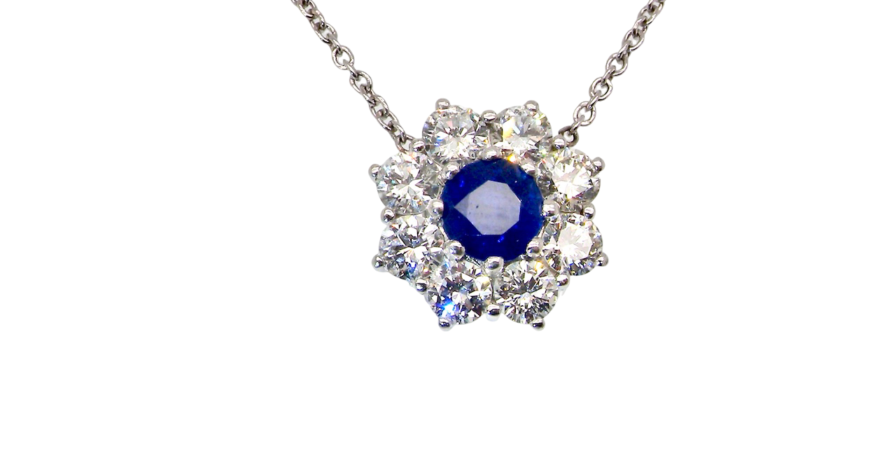 beautiful new 18 carat white gold cluster pendant, showcasing a blue sapphire at its centre.
