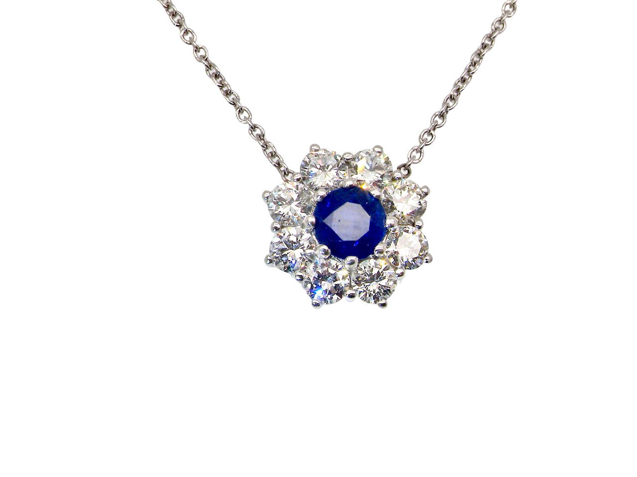 beautiful new 18 carat white gold cluster pendant, showcasing a blue sapphire at its centre.