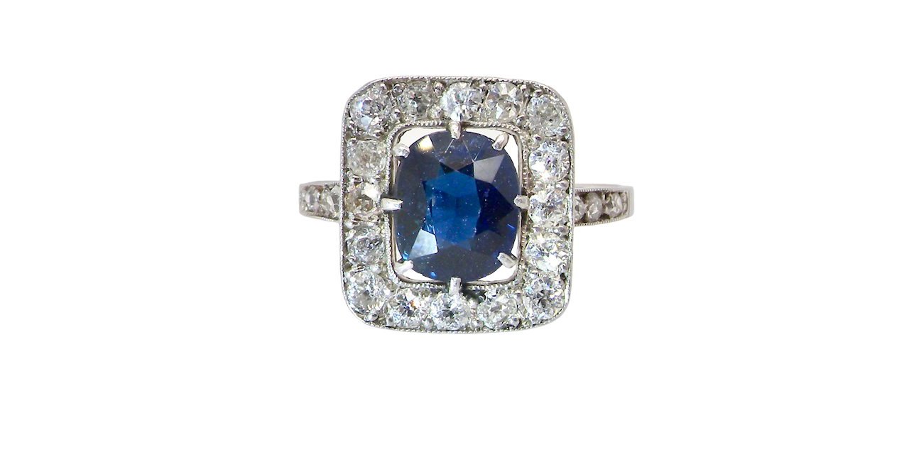 beautiful original Art Deco cluster ring featuring a dark blue oval-cut sapphire