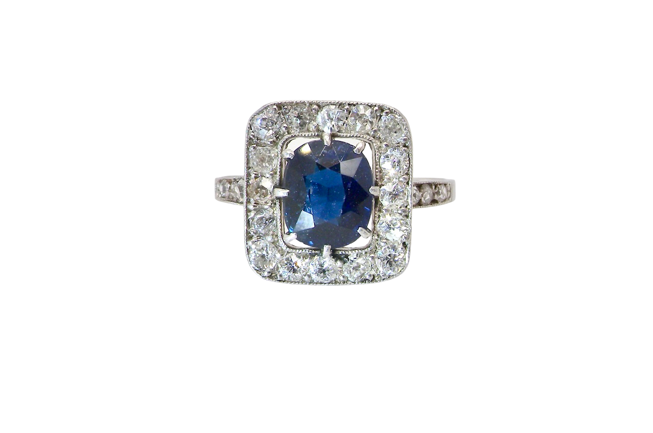 beautiful original Art Deco cluster ring featuring a dark blue oval-cut sapphire