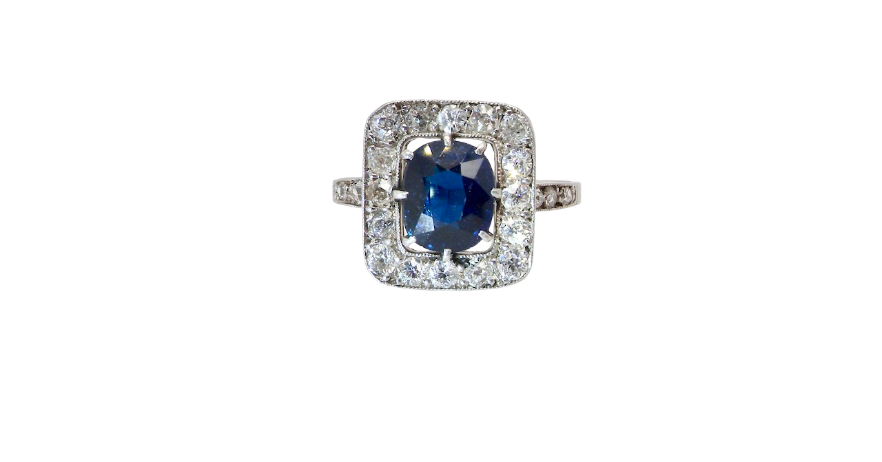 beautiful original Art Deco cluster ring featuring a rich, dark blue oval-cut sapphire