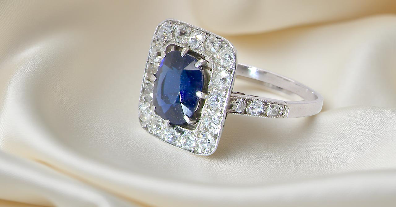 beautiful original Art Deco cluster ring featuring a rich, dark blue oval-cut sapphire side