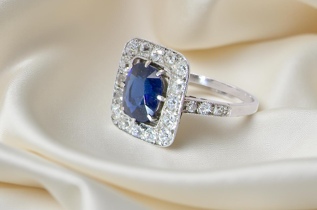 beautiful original Art Deco cluster ring featuring a rich, dark blue oval-cut sapphire side