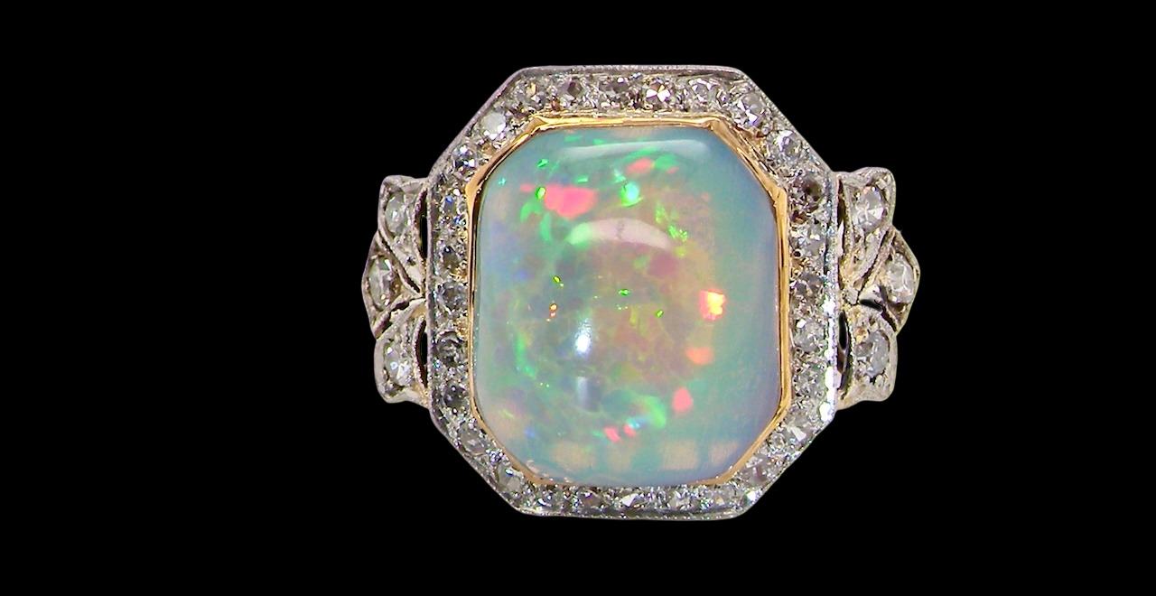 cabouchon cut opal shown is cushion shaped, measures 15x13 (5.78 carats) displaying a mass of vibrant colours, from flashes of fireglow orange, greens, and lavender purples.