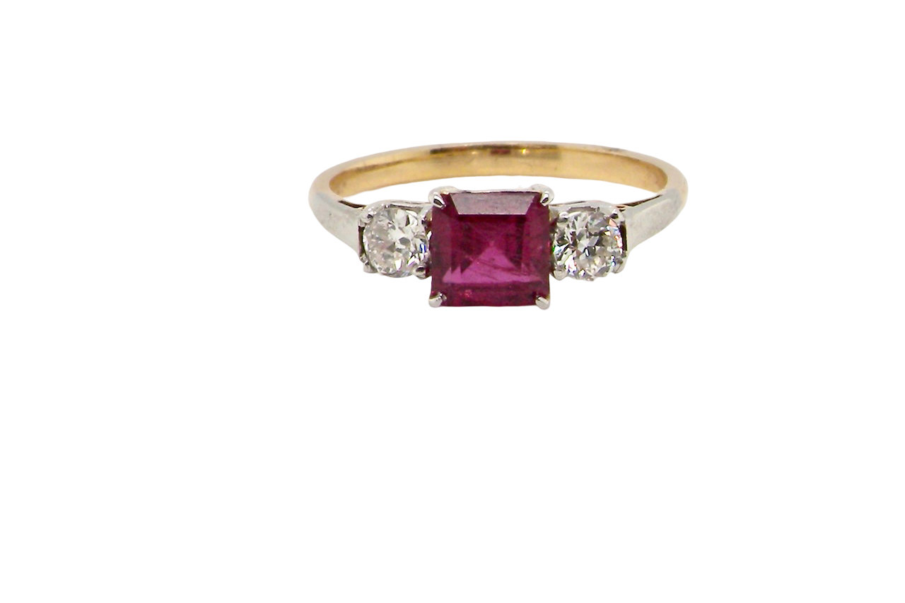 Gold ring with a red gemstone and two smaller diamonds on a white background