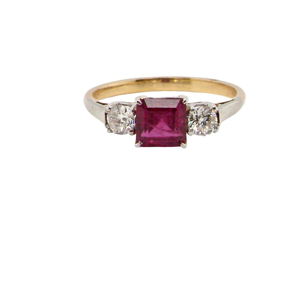 Gold ring with a red gemstone and two smaller diamonds on a white background