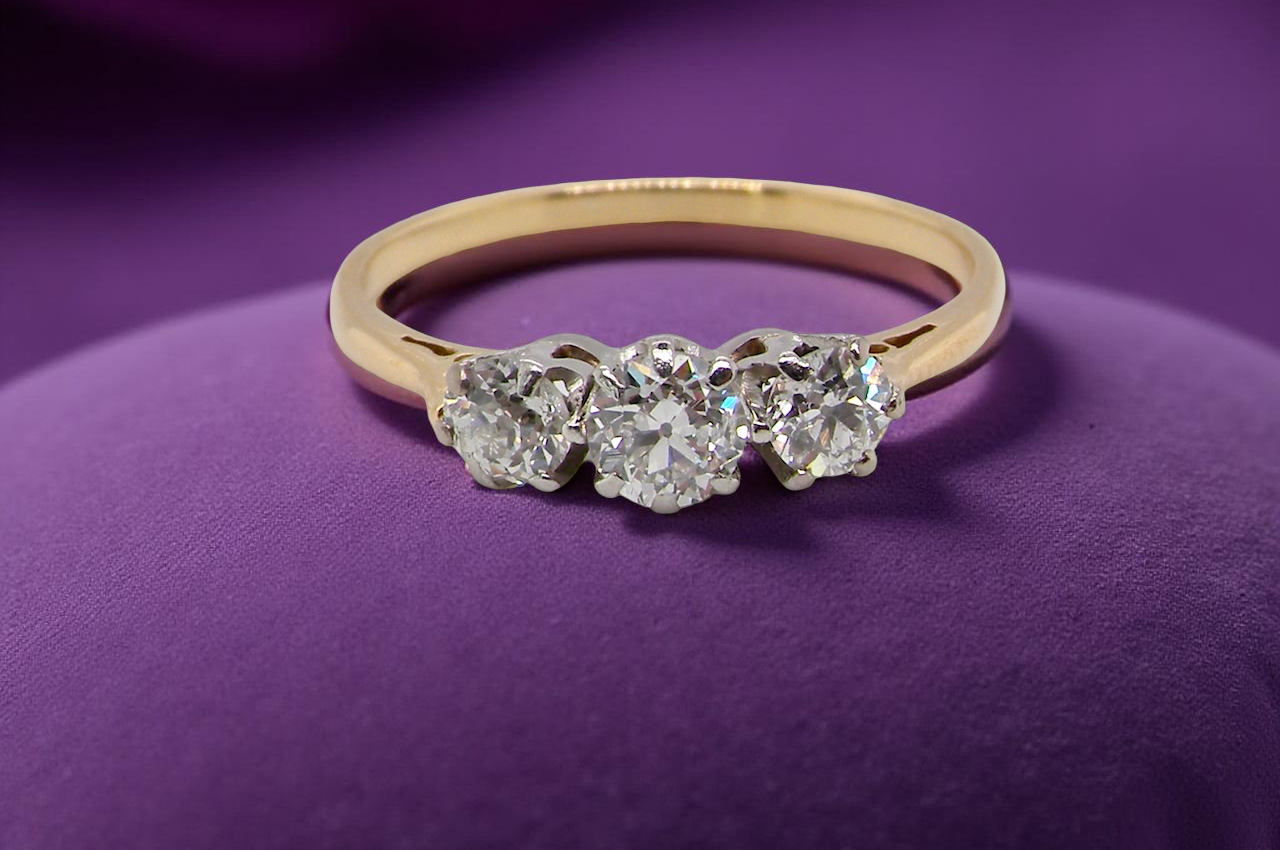 Gold ring with three diamonds on a purple background